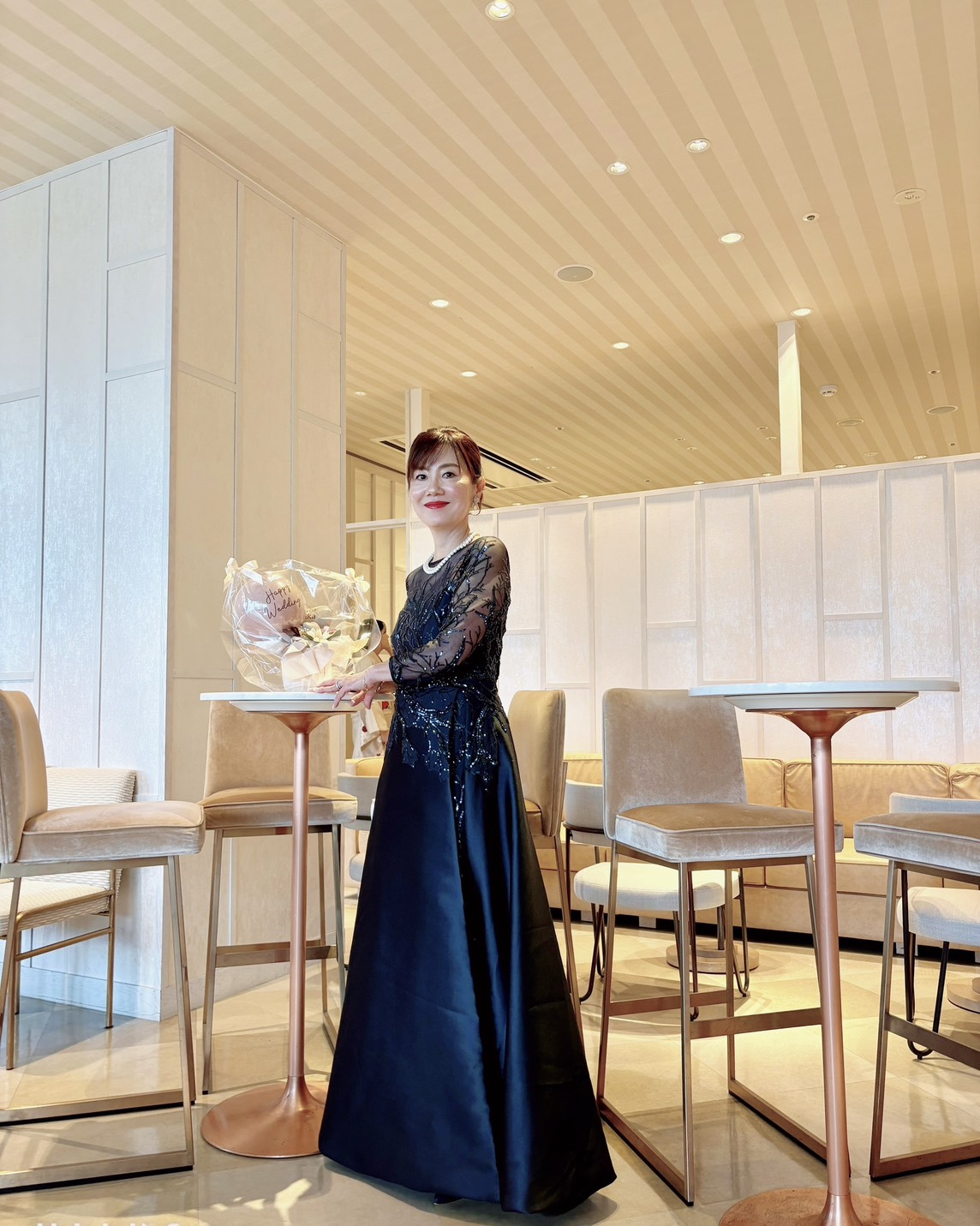 ネイビーのレース×トレーンドレスを着用した新郎母の全身ショット。パールアクセサリーとアップヘアを合わせた上品でフォーマルな結婚式スタイル。